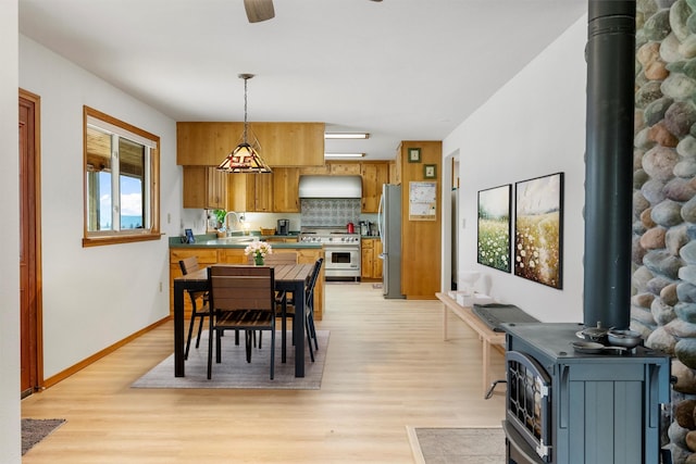 674 Porter Hill Rd, Stevensville, MT 59870 - dining area featuring a wood stove, light wood-type flooring, and a ceiling fan