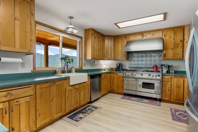 674 Porter Hill Rd, Stevensville, MT 59870 - kitchen with exhaust hood, appliances with stainless steel finishes, light wood finished floors, backsplash, and brown cabinetry