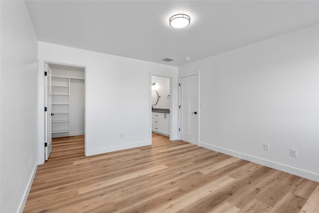 417 I St, Townsend, MT 59644 - unfurnished bedroom featuring a walk in closet, light wood finished floors, ensuite bathroom, and a closet