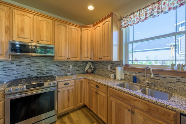 10487 Coulter Pine St, Lolo, MT 59847 - kitchen featuring appliances with stainless steel finishes, decorative backsplash, light stone counters, and light wood-style floors