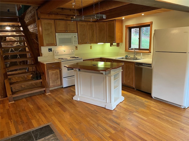 22550 Hill Rd, Clinton, MT 59825 - kitchen featuring white appliances, light wood-style floors, a center island, beamed ceiling, and brown cabinetry