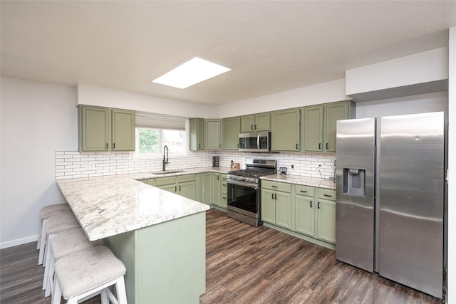 51 Konley Dr, Kalispell, MT 59901 - kitchen with green cabinetry, appliances with stainless steel finishes, a peninsula, dark wood-style flooring, and a kitchen bar