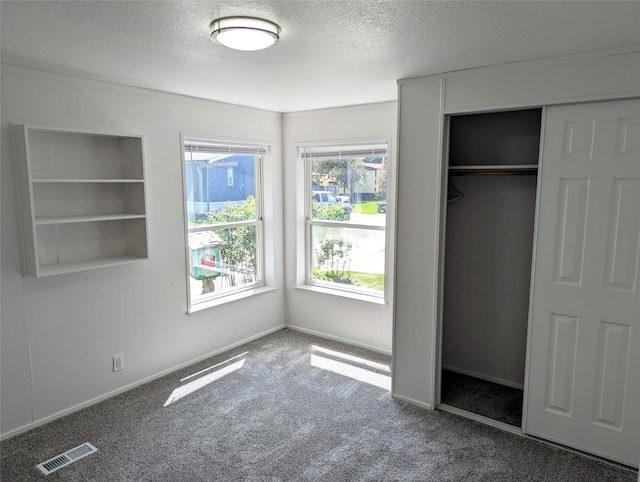 47 Merlin Dr, Bozeman, MT 59718 - unfurnished bedroom with a textured ceiling, carpet flooring, multiple windows, and a closet