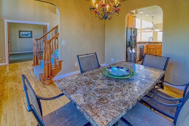 396 Wild Moose Springs Rd, Corvallis, MT 59828 - dining space featuring arched walkways, a chandelier, light wood finished floors, and stairs