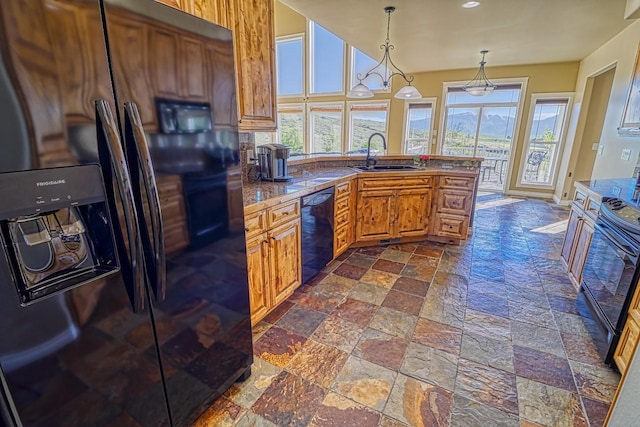 396 Wild Moose Springs Rd, Corvallis, MT 59828 - kitchen with black appliances, stone tile floors, brown cabinetry, hanging light fixtures, and decorative backsplash