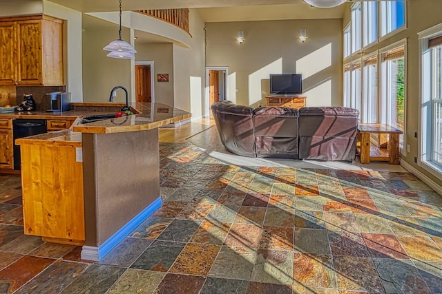 396 Wild Moose Springs Rd, Corvallis, MT 59828 - kitchen with stone tile floors, a high ceiling, brown cabinetry, a peninsula, and decorative light fixtures