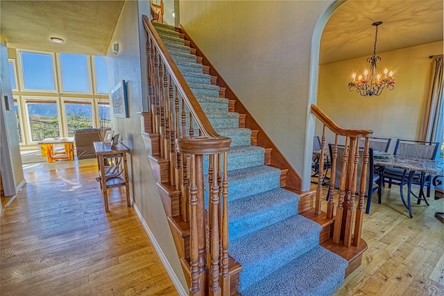 396 Wild Moose Springs Rd, Corvallis, MT 59828 - staircase with hardwood / wood-style flooring, arched walkways, a chandelier, and a high ceiling