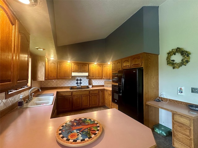 952 Chestnut Ave, Highwood, MT 59450 - kitchen with black appliances, decorative backsplash, vaulted ceiling, under cabinet range hood, and brown cabinetry
