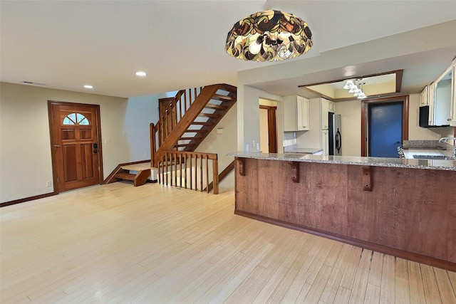 251 Elk Trl, Whitefish, MT 59937 - kitchen with white cabinets, freestanding refrigerator, light stone countertops, light wood-style floors, and recessed lighting
