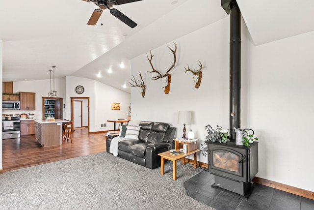 44 Kamloops Rd, Power, MT 59468 - living area featuring a wood stove, ceiling fan, vaulted ceiling, dark colored carpet, and dark wood-style floors