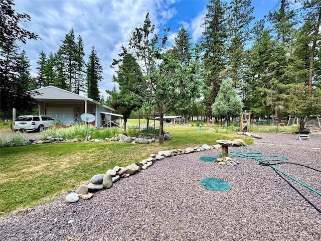 676 Rawlings Rd, Libby, MT 59923 - view of grassy yard with a detached garage, an outdoor structure, and view of wooded area