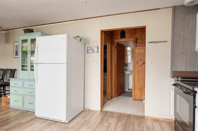 29276 White Swan Rd, Polson, MT 59860 - kitchen featuring freestanding refrigerator, electric range oven, light wood finished floors, and wooden walls