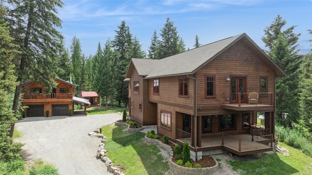 220 Cliff Creek Rd, Whitefish, MT 59937 - view of front of home with gravel driveway, covered porch, a shingled roof, an attached garage, and a front yard