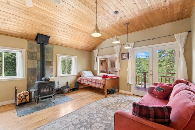 220 Cliff Creek Rd, Whitefish, MT 59937 - bedroom featuring access to exterior, a wood stove, multiple windows, wood-type flooring, and vaulted ceiling