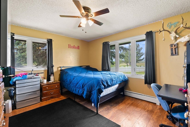 149 Meadow Vista Ln, Deer Lodge, MT 59722 - bedroom with a baseboard heating unit, a textured ceiling, wood finished floors, and ceiling fan