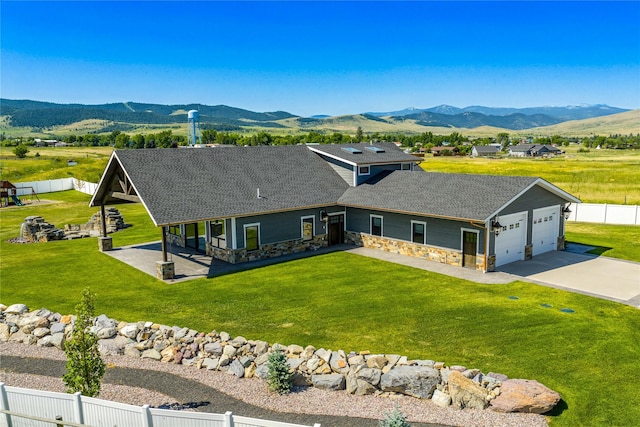 60951 Sparky Dr, Saint Ignatius, MT 59865 - view of front of house with stone siding, a mountain view, an attached garage, a shingled roof, and concrete driveway