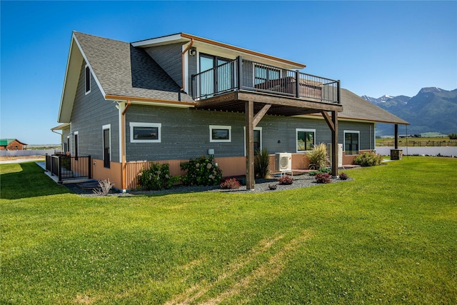 60951 Sparky Dr, Saint Ignatius, MT 59865 - back of property featuring a mountain view, a yard, a shingled roof, and a balcony