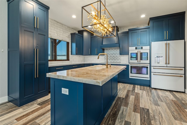 60951 Sparky Dr, Saint Ignatius, MT 59865 - kitchen with white appliances, blue cabinets, wall chimney exhaust hood, backsplash, and a chandelier