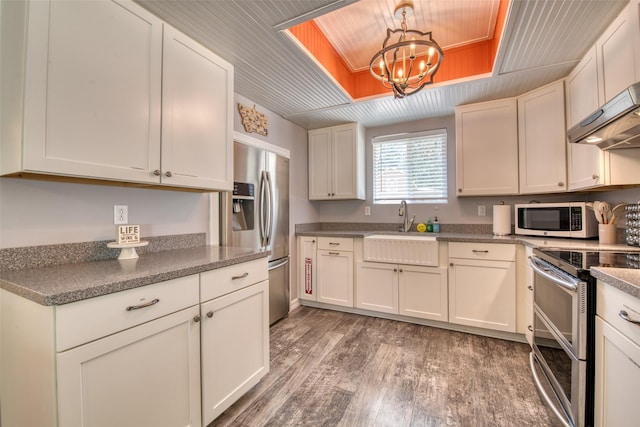 409 Mill Creek Rd, Hamilton, MT 59840 - kitchen featuring appliances with stainless steel finishes, light wood-style floors, wall chimney exhaust hood, a chandelier, and white cabinets