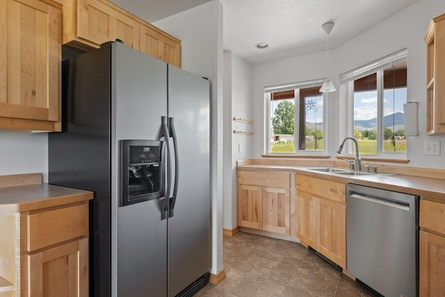 1228 Nordheim Ln, Corvallis, MT 59828 - kitchen featuring appliances with stainless steel finishes, light brown cabinetry, and hanging light fixtures