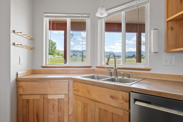 1228 Nordheim Ln, Corvallis, MT 59828 - kitchen with stainless steel dishwasher, light countertops, light brown cabinets, decorative light fixtures, and a mountain view