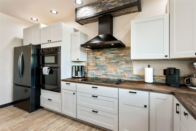 600 Ringneck Dr, Kalispell, MT 59901 - kitchen with black appliances, wood counters, wall chimney exhaust hood, tasteful backsplash, and light wood-type flooring