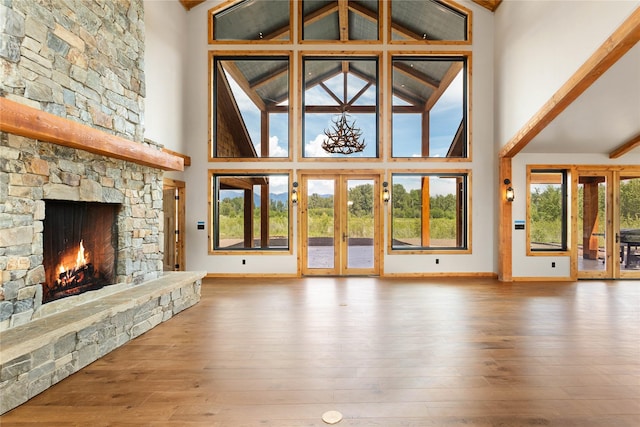 600 Ringneck Dr, Kalispell, MT 59901 - unfurnished living room featuring high vaulted ceiling, hardwood / wood-style flooring, french doors, a stone fireplace, and beam ceiling