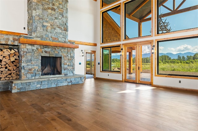 600 Ringneck Dr, Kalispell, MT 59901 - unfurnished living room featuring a towering ceiling, a stone fireplace, hardwood / wood-style flooring, and french doors