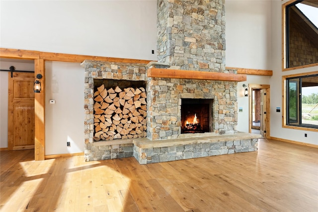 600 Ringneck Dr, Kalispell, MT 59901 - unfurnished living room with hardwood / wood-style floors, a towering ceiling, a stone fireplace, and a barn door