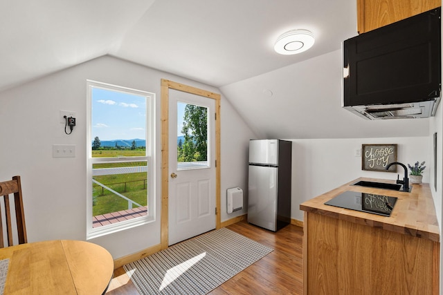 1380 Lower Valley Rd, Kalispell, MT 59901 - kitchen featuring freestanding refrigerator, wood counters, black electric cooktop, vaulted ceiling, and light wood-style floors