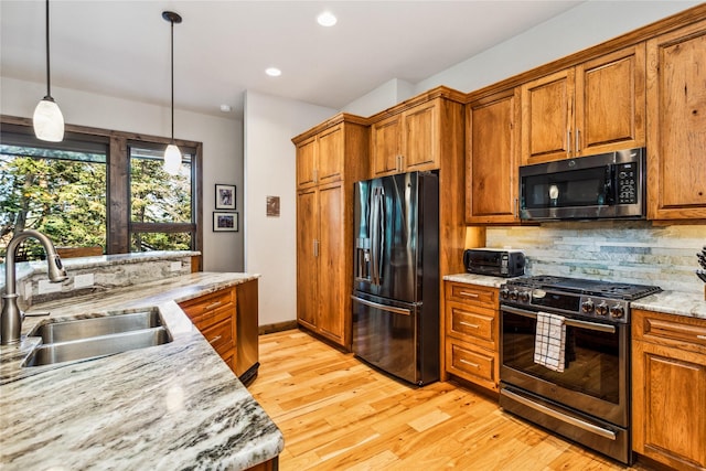 33731 Westview Dr, Bigfork, MT 59911 - kitchen featuring black fridge with ice dispenser, stainless steel range with gas cooktop, brown cabinetry, light wood-style floors, and recessed lighting