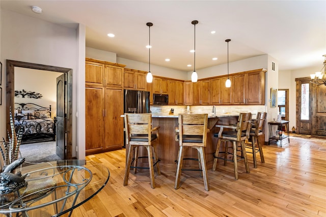 33731 Westview Dr, Bigfork, MT 59911 - kitchen featuring black microwave, light wood-style floors, backsplash, stainless steel fridge, and pendant lighting