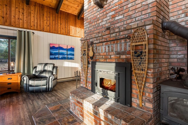 630 Tally Lake Rd, Whitefish, MT 59937 - living area featuring a wood stove, a wood ceiling with exposed beams, wood-type flooring, wood walls, and a lit fireplace