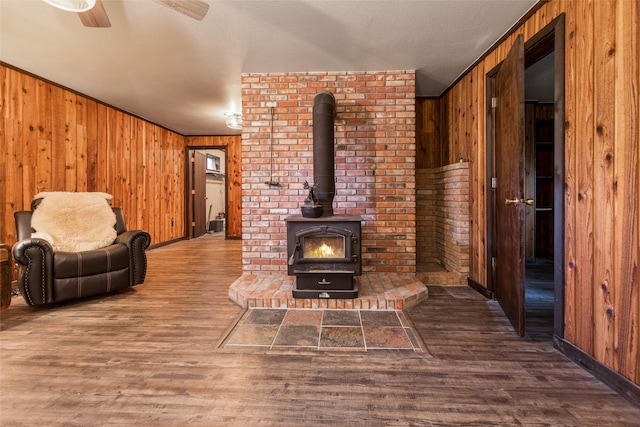 630 Tally Lake Rd, Whitefish, MT 59937 - living area featuring wooden walls, wood finished floors, a ceiling fan, and a wood stove