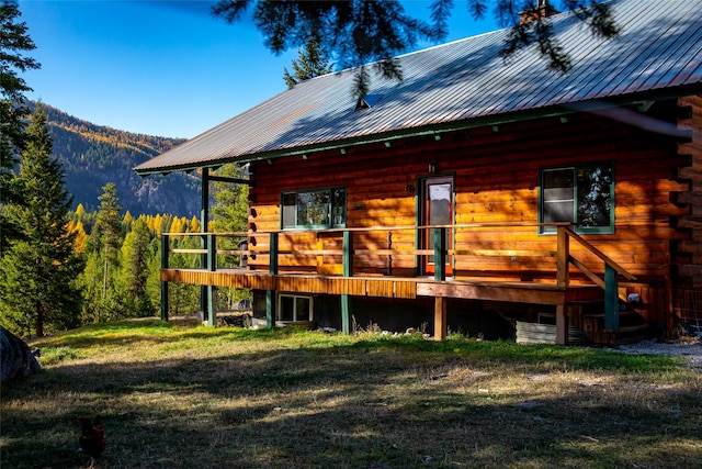 630 Tally Lake Rd, Whitefish, MT 59937 - rear view of house with log siding, a metal roof, a lawn, and a deck with mountain view