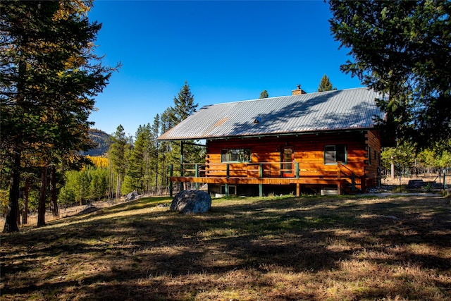 630 Tally Lake Rd, Whitefish, MT 59937 - rear view of property featuring a wooden deck, a chimney, a yard, a metal roof, and log exterior