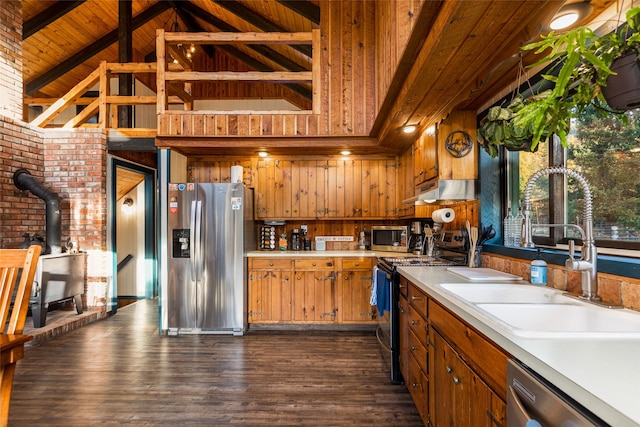 630 Tally Lake Rd, Whitefish, MT 59937 - kitchen featuring stainless steel appliances, a wood stove, light countertops, a wooden ceiling with exposed beams, and brown cabinets