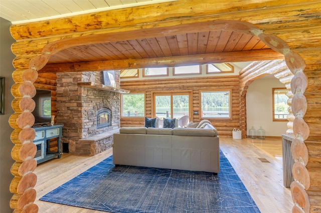 2755 US Highway 93 W, Whitefish, MT 59937 - living room featuring rustic walls, a wooden ceiling with exposed beams, a stone fireplace, and dark wood-type flooring