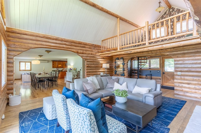 2755 US Highway 93 W, Whitefish, MT 59937 - living room featuring arched walkways, high vaulted ceiling, radiator heating unit, log walls, and hardwood / wood-style flooring