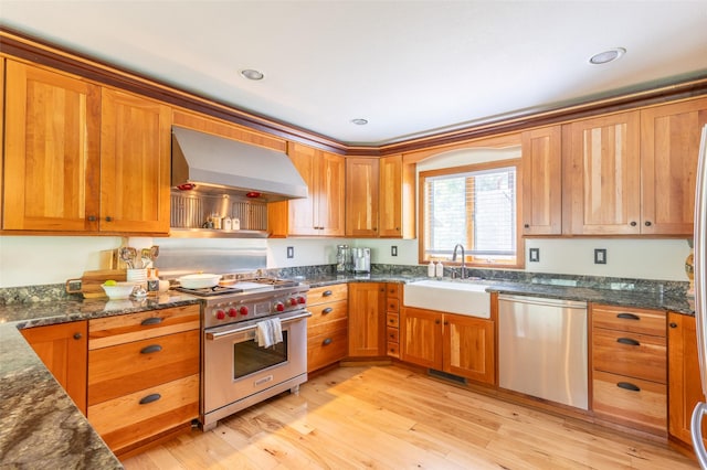 2755 US Highway 93 W, Whitefish, MT 59937 - kitchen with stainless steel appliances, wall chimney exhaust hood, dark stone counters, and light wood finished floors