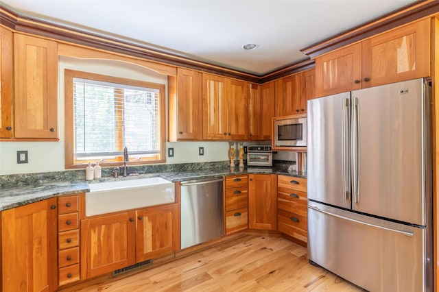 2755 US Highway 93 W, Whitefish, MT 59937 - kitchen featuring appliances with stainless steel finishes, light wood-style floors, brown cabinets, and dark stone countertops