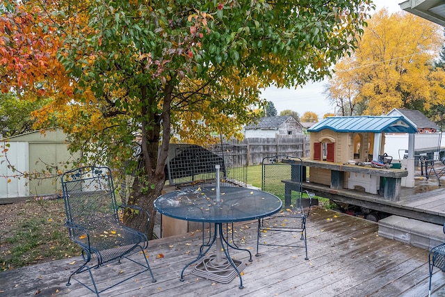 609 11th Ave E, Polson, MT 59860 - wooden terrace featuring outdoor dining area, a fenced backyard, and an outbuilding