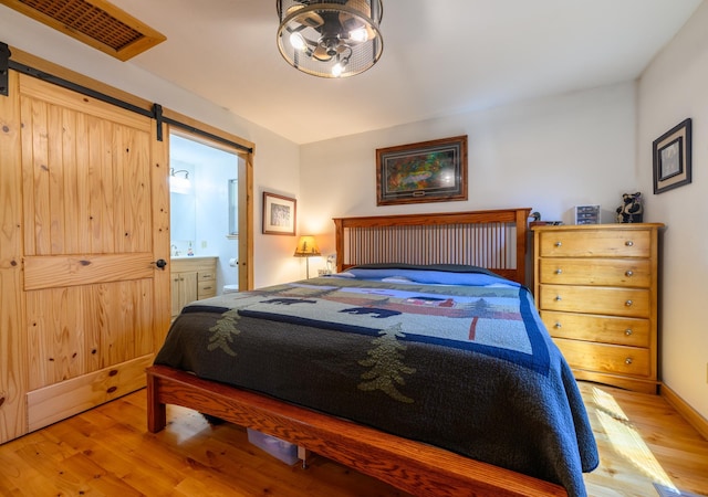 192 Leonard Ln, Eureka, MT 59917 - bedroom featuring wood finished floors, a barn door, and ensuite bath