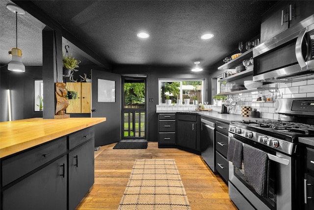438 Somers Ave, Whitefish, MT 59937 - kitchen with stainless steel appliances, wooden counters, a textured ceiling, decorative backsplash, and light wood-style flooring