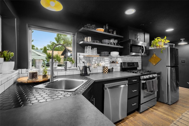 438 Somers Ave, Whitefish, MT 59937 - kitchen featuring appliances with stainless steel finishes, dark cabinets, backsplash, light wood-style floors, and dark countertops
