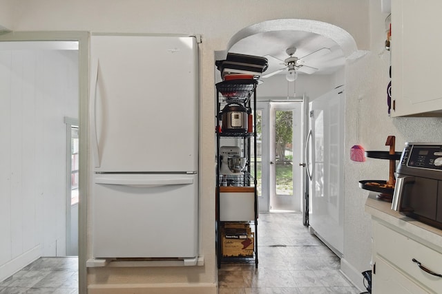 3120 1st Ave N, Great Falls, MT 59401 - kitchen featuring freestanding refrigerator, ceiling fan, white cabinetry, and arched walkways