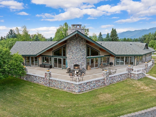 639 Three Eagle Ln, Bigfork, MT 59911 - rear view of property featuring a yard, a patio, a mountain view, and stone siding