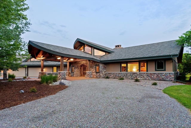 639 Three Eagle Ln, Bigfork, MT 59911 - view of front of property featuring covered porch, stone siding, driveway, and a chimney