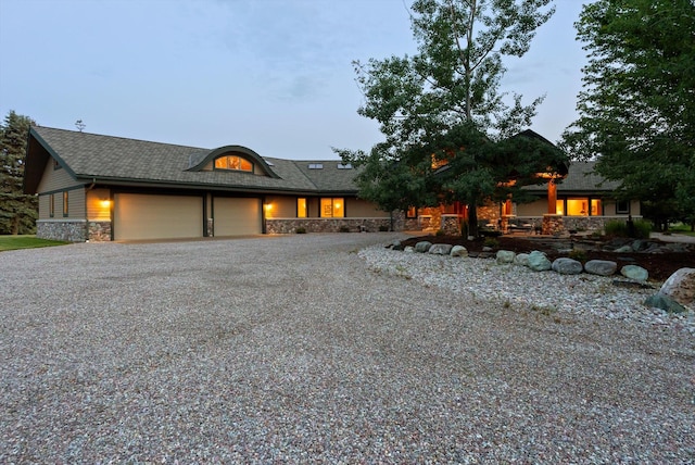 639 Three Eagle Ln, Bigfork, MT 59911 - view of front of home with stone siding, an attached garage, and gravel driveway