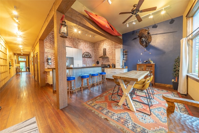439 Osborn Ave Unit 115, Bigfork, MT 59911 - dining space featuring brick wall, rail lighting, wood-type flooring, ceiling fan, and healthy amount of natural light